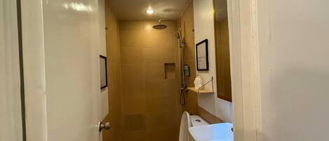 A small bathroom with a toilet, shower, and a white sink.
