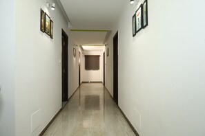 A corridor with framed pictures on the walls, a door at the end, and a light fixture on the ceiling. - Welcoming 11-bedroom hotel with AC in vibrant Ahmedabad (Ahmedabad)