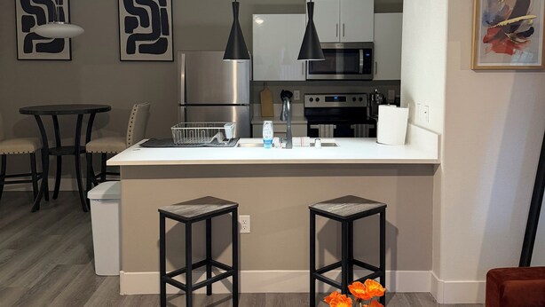 Une cuisine moderne dotée d’un îlot central, de luminaires suspendus et d’un coin repas avec des chaises.