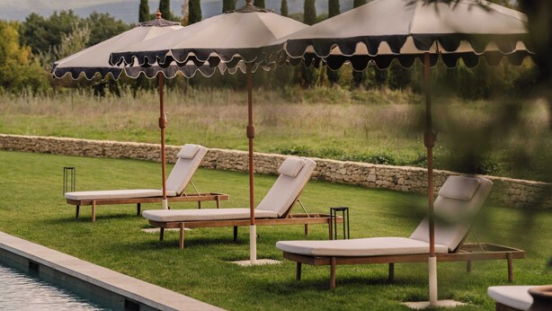 A poolside area with lounge chairs and umbrellas, surrounded by greenery and a view of distant hills. - Luxury Provencal House - Pool, Nature & spa (Villes-sur-Auzon)