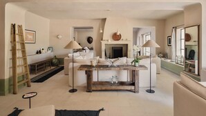 A living room with a fireplace, white sofas, a coffee table, and a ladder against the wall. - Luxury Provencal House - Pool, Nature & spa (Villes-sur-Auzon)