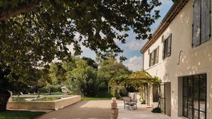 A courtyard with a patio, a pergola, and a building with large windows. - Luxury Provencal House - Pool, Nature & spa (Villes-sur-Auzon)