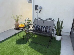 A metal bench with a cushion, a potted plant, and a bowl of fruit on a small table. - FIFA 2026 Modern Luxury Stay-Minutes to SoFi (Inglewood)