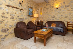Une pièce chaleureuse avec des murs en pierre, une table basse en bois, des canapés en cuir et une lampe.