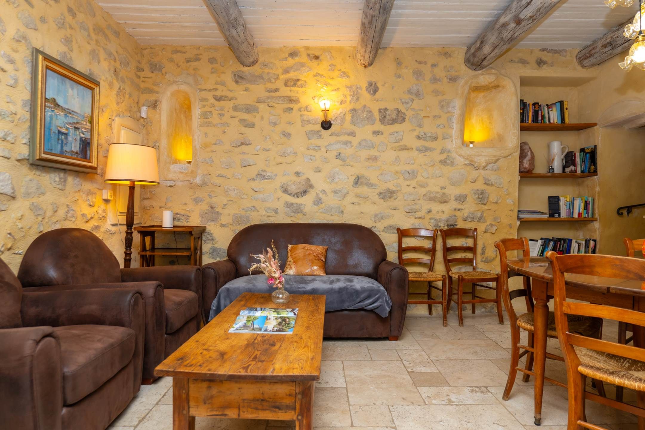 A cozy living room with a stone wall, leather furniture, and a bookshelf.