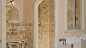 A bathroom with a tiled shower, a sink with a metal frame, and a window with a towel hanging on the wall. - Luberon Cottage at Château Juvenal (Saint-Hippolyte-le-Graveyron)