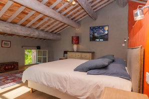 Une chambre à coucher avec un lit, une commode, une lampe, un tableau et une fenêtre.