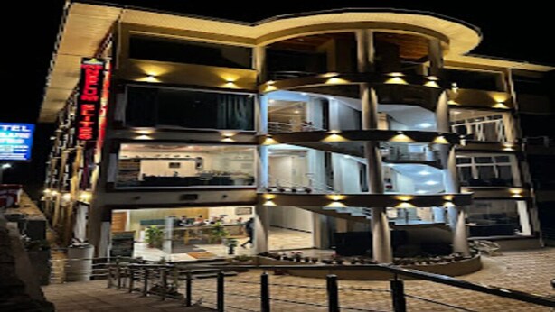 A multi-story hotel with balconies, a visible restaurant, and a sign indicating a hotel. - Hotel Neelum Elites (Athmuqam)