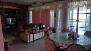 A living room with a sofa, a glass-top dining table, and a television.