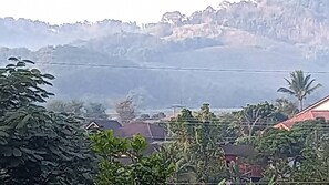 Quartiere residenziale con case, una linea elettrica e una montagna sullo sfondo.