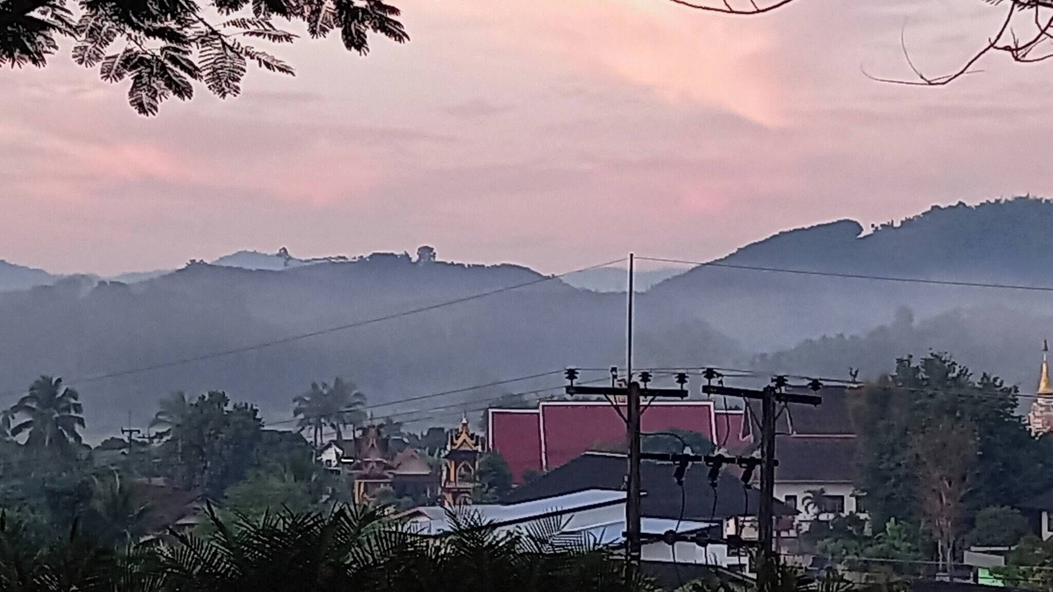 Un barrio residencial con casas, líneas eléctricas y una colina al fondo.