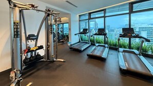 A gym with treadmills, weight machines, and a city view. - eaton (Kuala Lumpur)