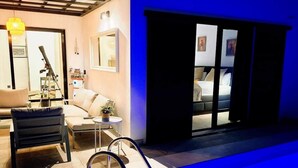 Quarto de hotel moderno com piscina, sofá, uma mesinha com planta e um telescópio.
