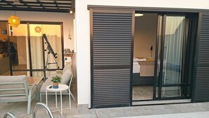 Uma área à beira da piscina com um espaço de estar, um telescópio e uma porta de correr de vidro que dá para um banheiro.