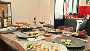 Mesa de jantar posta com diversos pratos, copos e uma garrafa de vinho.