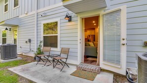 A residential building with a patio area featuring a table and chairs, a door leading to a living space, and an air conditioning unit. - Modern 3-Bedroom
Townhome with Pool Access (Pensacola)