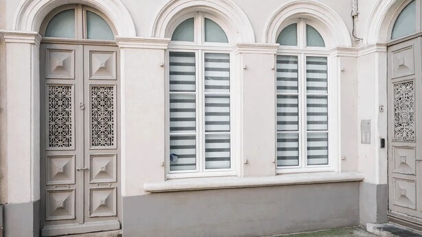 A building facade with three arched windows and a door with intricate metalwork. - Cosy studio at the foot of the ramparts (Boulogne-sur-Mer)