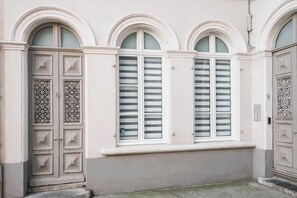 Une façade d’immeuble ornée de trois fenêtres en arc et d’une porte dont le décor métallique est particulièrement travaillé.