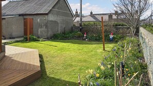 Une propriété résidentielle dotée d’une pelouse bien entretenue, de quelques statues de nains de jardin et d’une terrasse en bois.