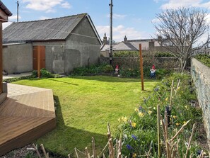 Ein Wohnhaus mit gepflegtem Rasen, Gartenzwergen und einer Holzterrasse.