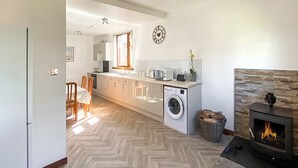 Une cuisine moderne dotée d’un îlot central, d’un lave-linge, d’une cheminée et d’un coin repas avec des chaises.