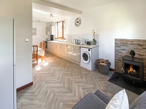 Eine moderne Küche mit Kochinsel, Waschmaschine, Kamin und Essbereich mit Stühlen.