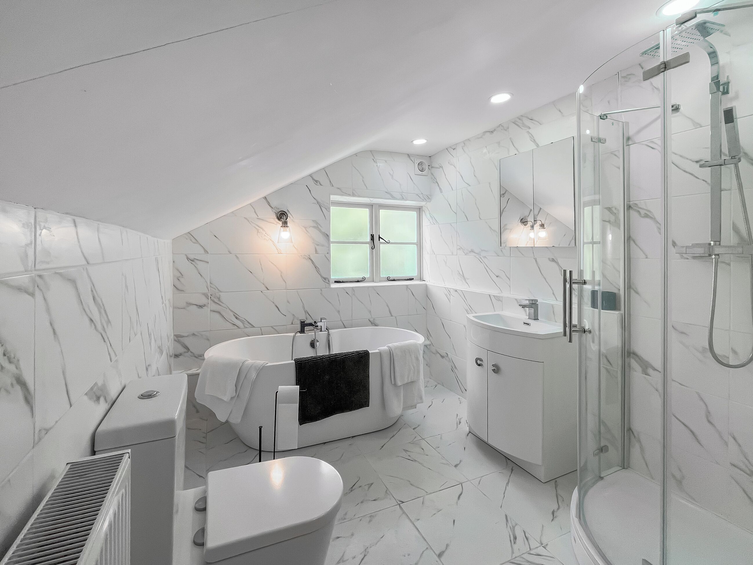 A modern bathroom with a freestanding bathtub, a glass-enclosed shower, and a vanity with a sink.
