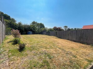 A fenced backyard with a small shed, a tree, and a wooden fence. - 4 bedroom accommodation in Alford, near Mablethorpe (Alford, near Mablethorpe)