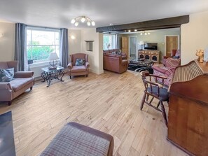 A spacious living room with a wooden floor, a sofa set, a coffee table, and a television. - 4 bedroom accommodation in Alford, near Mablethorpe (Alford, near Mablethorpe)