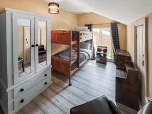 Habitación con literas, un armario, un escritorio y una ventana con cortinas.