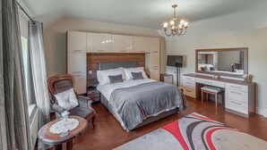 Un dormitorio con cama, escritorio, silla, cómoda, espejo y candelabro.