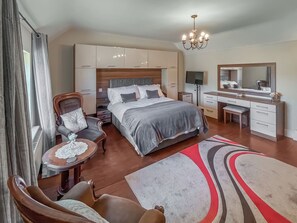 A bedroom with a bed, a desk, a chair, a dresser, a mirror, and a chandelier. - 4 bedroom accommodation in Alford, near Mablethorpe (Alford, near Mablethorpe)