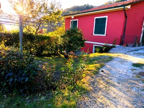 A red building with a gravel driveway and surrounding greenery. - Vacation home between Tuscany and Liguria: relaxation, nature and silence among the hills (Canepari)