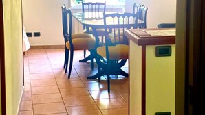 Un coin repas comprenant une table et des chaises, un lustre et une fenêtre avec des volets.