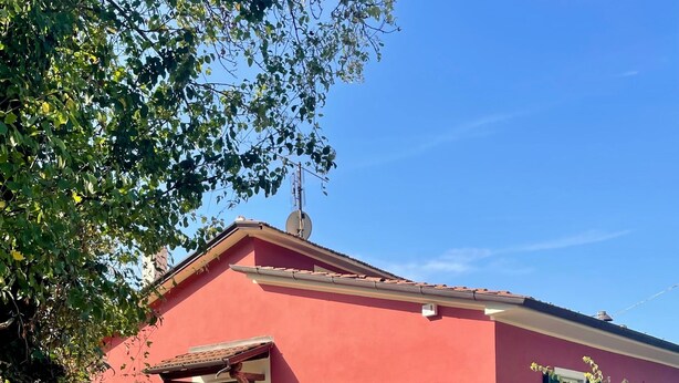 Un bâtiment rouge avec une porte verte, un chemin de gravier et une clôture en métal.