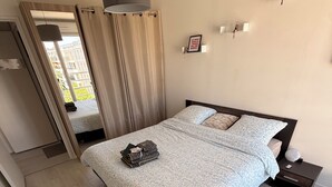 A modern bedroom with a bed, bedside table, and a standing fan. - Apartment + Parking in Paris, Massy (TGV/RER B/C, Orly Bus) (Massy)