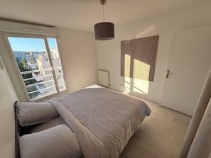 Een slaapkamer met een bed, een raam, een deur en een wandlamp.