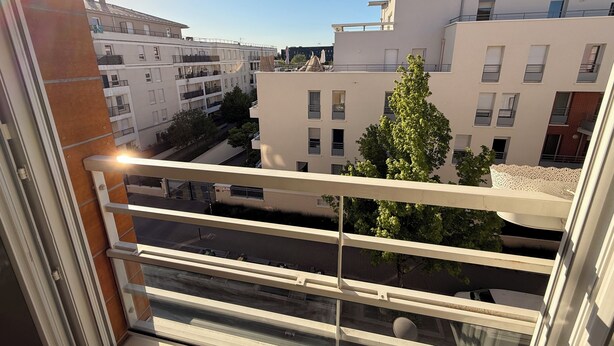 A view from a balcony overlooking a residential area with modern buildings, a clear sky, and a street below. - Apartment + Parking in Paris, Massy (TGV/RER B/C, Orly Bus) (Massy)