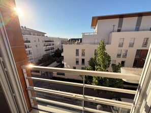 Uitzicht vanaf een balkon op een woongebied met moderne gebouwen, een heldere lucht en een straat eronder.