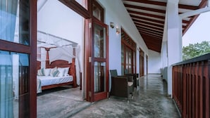 Ein Flur mit einem Bett, Korbmöbeln und Glastüren, die zu einem Schlafzimmer führen.