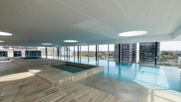 Une piscine intérieure spacieuse offrant une vue sur les bâtiments environnants.