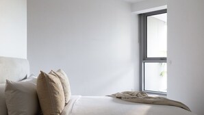 Une chambre à coucher au style minimaliste, avec un lit, des oreillers et une fenêtre.