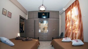 Ein Hotelzimmer mit zwei Betten, einem Kleiderschrank, einem Fernseher und einem Spiegel.