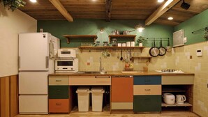 Een keuken met een koelkast, oven, magnetron, spoelbak en diverse keukengerei.