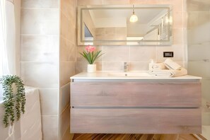 A bathroom with a white vanity, a mirror, a potted plant, a towel, and a soap dispenser. - Via D'andrade Sestri Ponente (Genoa)