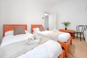 A hotel room with two beds, a desk, a chair, and a potted plant. - Via D'andrade Sestri Ponente (Genoa)