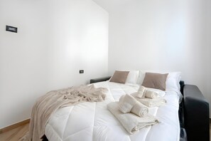 Una cama bien hecha con edredón, almohadas y toallas dobladas.