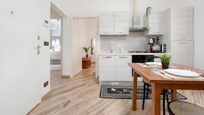 Eine moderne Küche mit weißen Schränken, einem Holztisch und einem schwarz-weißen Teppich.
