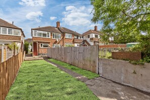 A residential area with houses, a wooden fence, and a grassy yard. - Stylish Catford Maisonette + Free Parking (London)