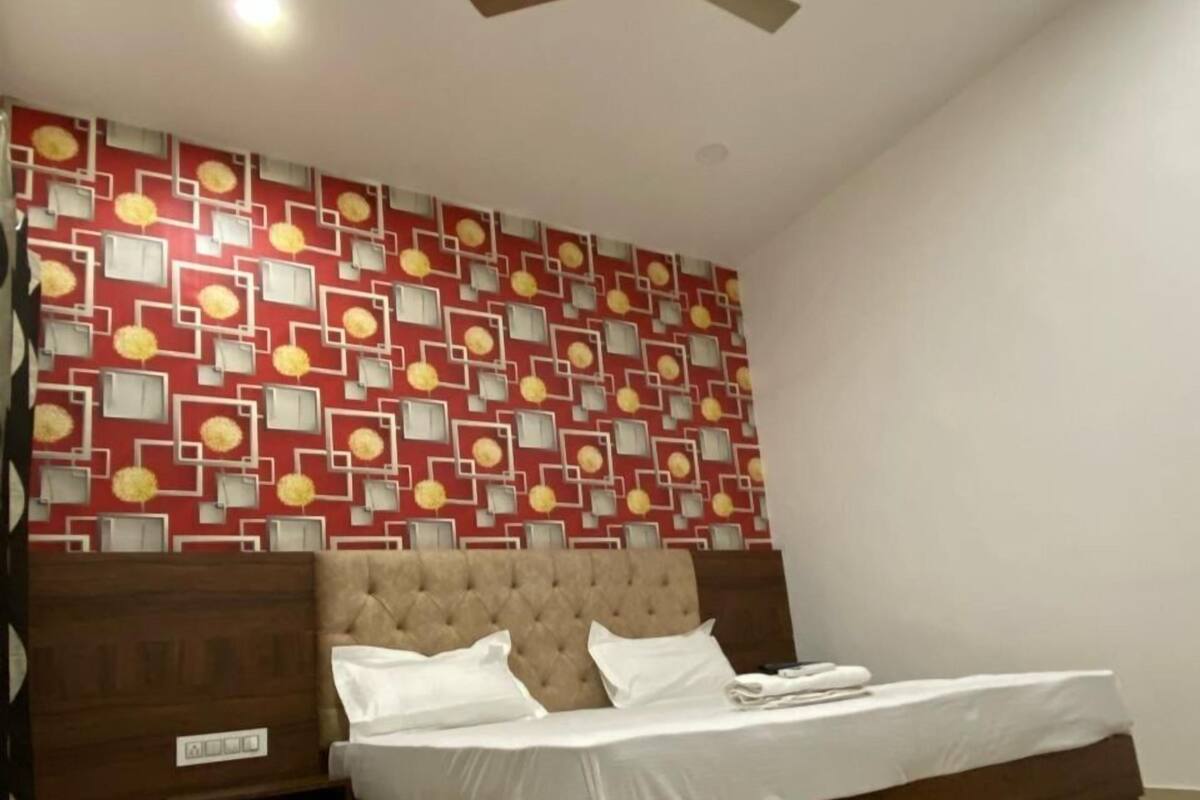 Un dormitorio con cama, ventilador de techo, pared estampada y cabecera de madera.